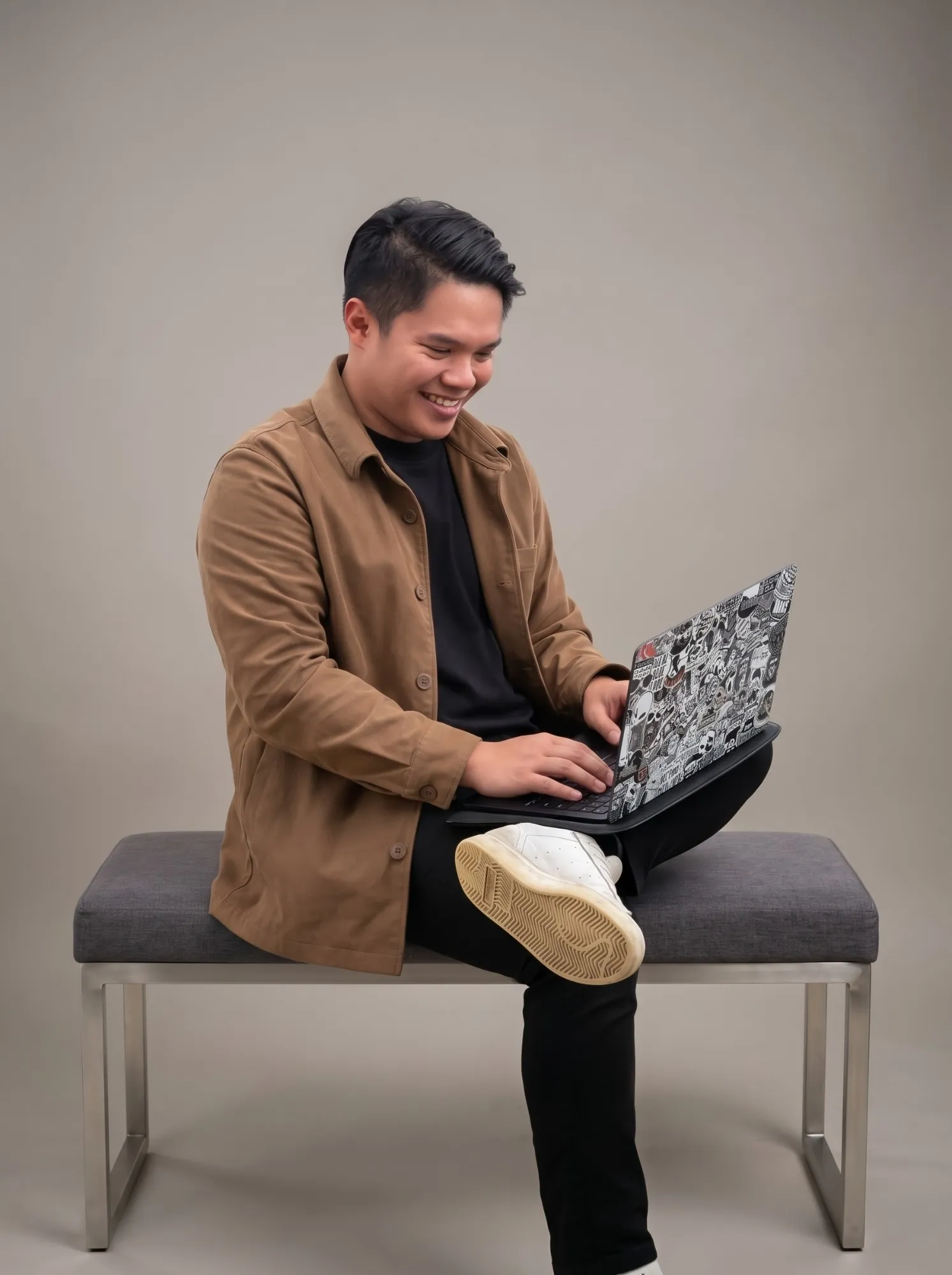 Kurt Gattud, founder of Gattud Design Studio, smiling as he works on a laptop